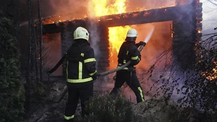 ARCHIV - Feuerwehrleute löschen ein Feuer, nachdem ein Haus von russischem Beschuss getroffen wurde. Foto: Andrii Marienko/AP/dpa
