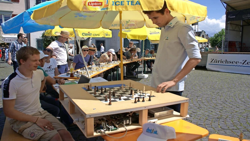 Simultanturnier: Klubmitglieder und Interessierte treten an 25 Brettern gegen den Grossmeister Nico Georgiadis (rechts) an – auch ein Schachroboter spielt mit (der junge Mann links studiert Informatik an der ETH und hat den Roboter entwickelt).